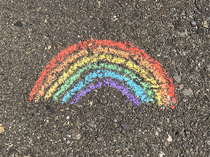 A colourful chalk rainbow on a pavement.