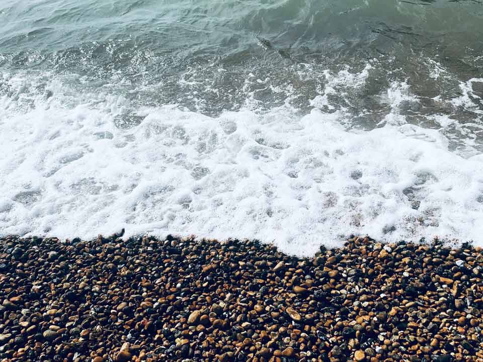 Point of view of the sea breaking on a Brighton's pebble beach.